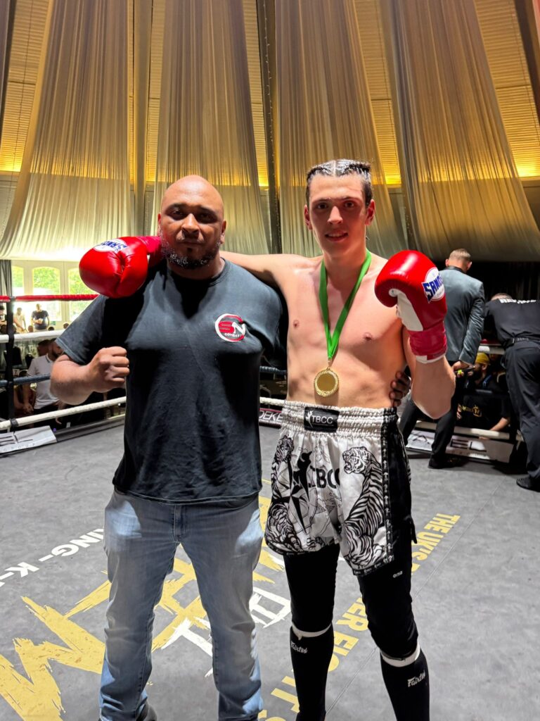 Shazhaib wearing his winners medal standing next to his headcoach Khru Sam Nankani