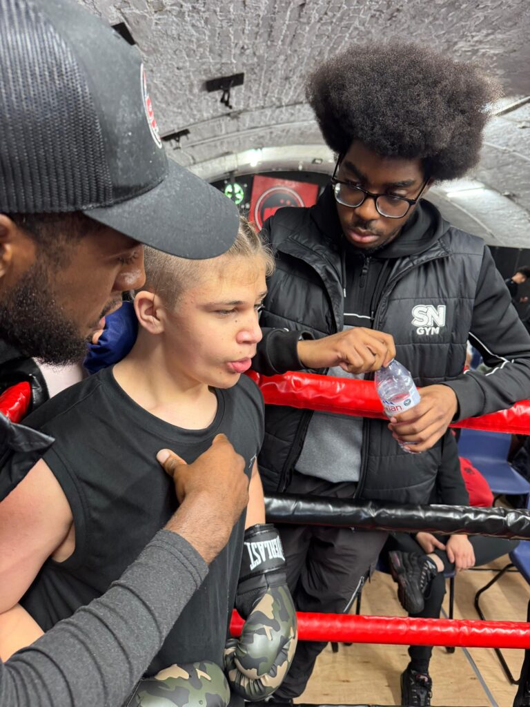 Instructor Nathan Lewis and assistant Instructor Bemvindo Rosa giving instructions to junior academy fighter