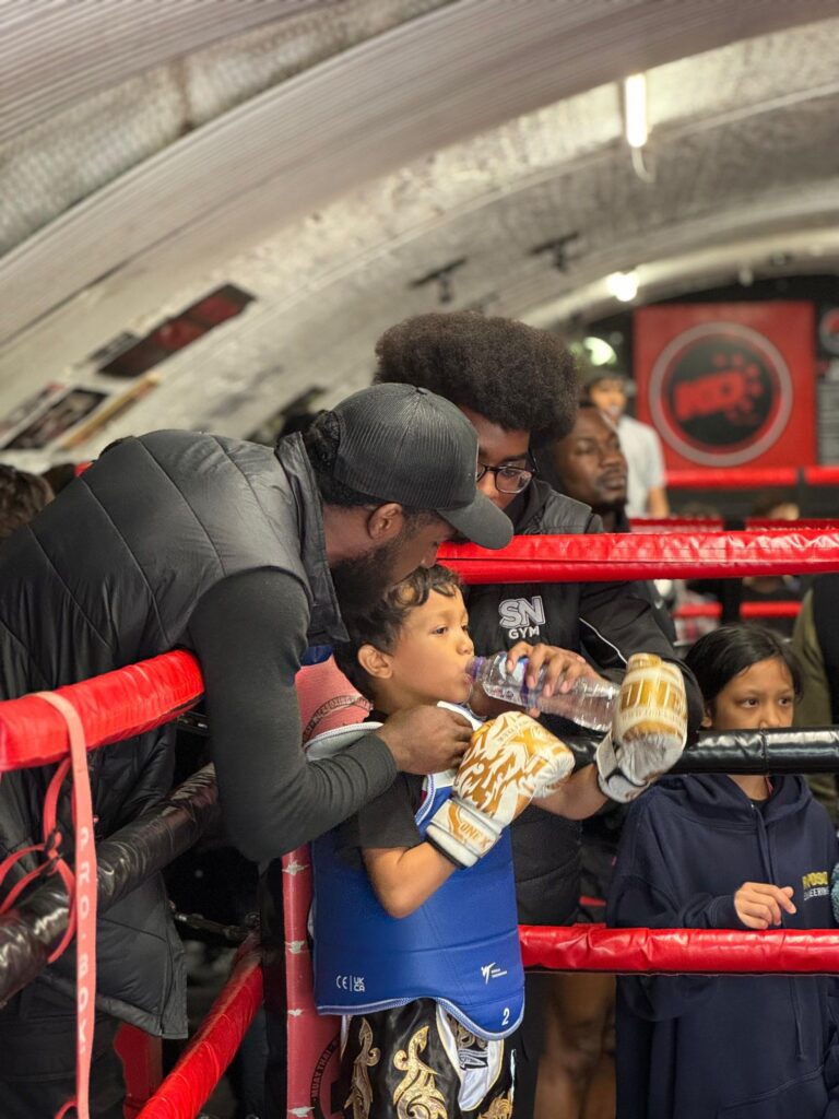Instructor Nathan Lewis and assistant Instructor Bemvindo Rosa in ring corner with youngest SN Combat academy fighter